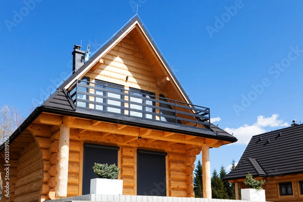 Fototapeta Nice wooden house with a balcony, on a hill under a blue sky