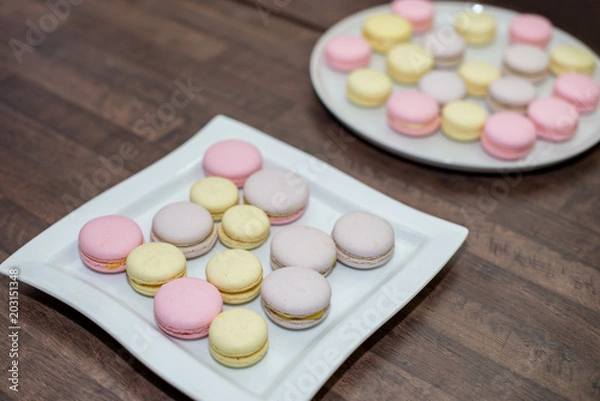 Fototapeta Colorful French or Italian macarons stack on white plate put on wood table with copy space for background.