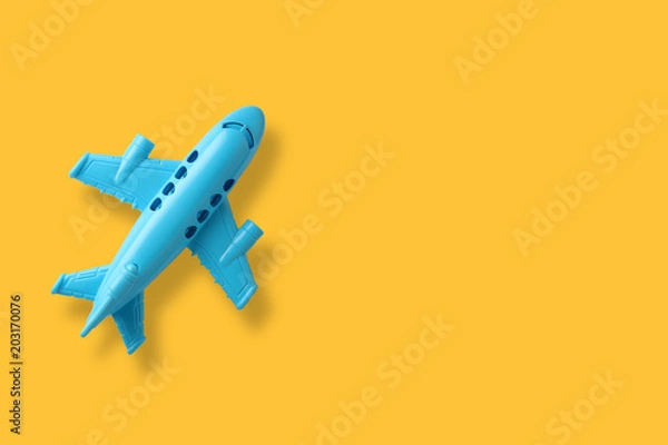 Fototapeta blue plastic toy plane on yellow background with space
