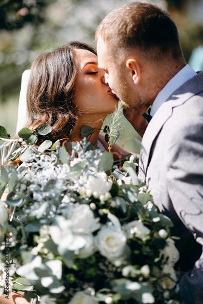 Obraz The first meeting of the bride and groom on their wedding day in the garden. Waiting and emotions of the newlyweds. The first kiss of the bride and groom