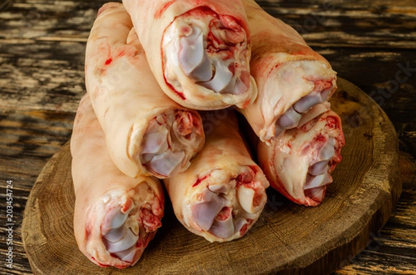 Obraz Raw and freesh pork feet or legs,over dark wooden board. They are stacked pile. Food meat shot.