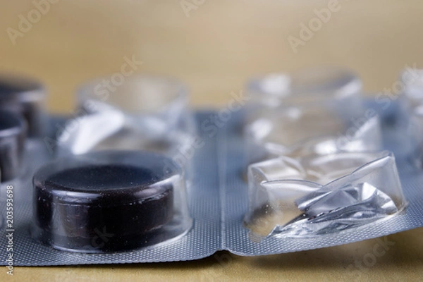 Fototapeta Pills in a wrapper on a wooden table. A medicine for a cold and a headache in a plastic package.