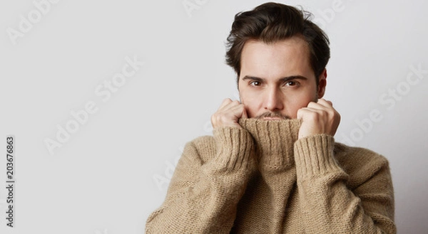 Fototapeta Portrait of young fashion model in pullover sweater poising while standing on white background. Horizontal