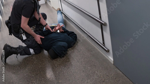 Fototapeta Prison guard right inmate resisting arrest in prison after commiting crime.