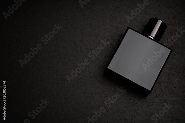 Fototapeta Mockup of black fragrance perfume bottle mockup on dark empty background. Top view. Horizontal