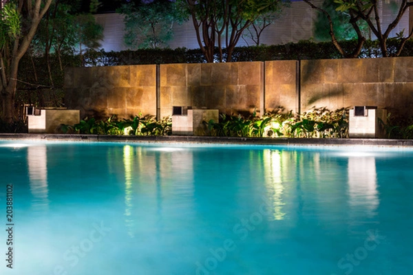 Fototapeta Lush pool lighting in backyard for luxury swimming pool design created by great lighting professionals.