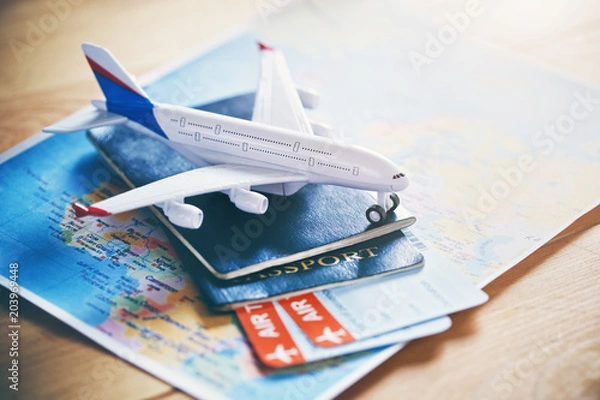 Fototapeta Plane model with world map, passports and tickets as airplane traveling and tickets booking concept