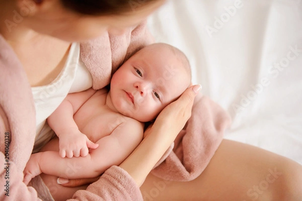 Obraz Mother holding small child in her arms. Baby love concept. Tenderness and care. Nursing infants. View from above
