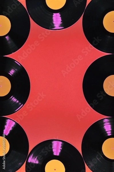 Fototapeta old black vinyl records with blank orange labels on red background as frame