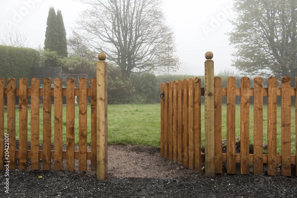 Fototapeta Open wooden gate and fence leading into a garden 