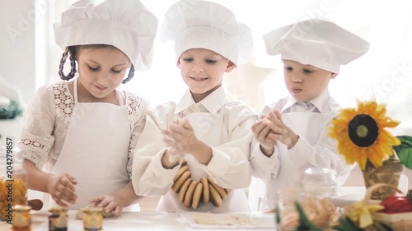 Fototapeta Happy little children in the shape of a chef to prepare delicious dishes