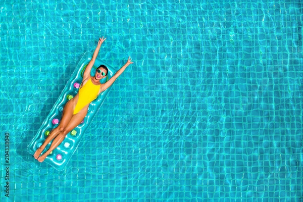 Fototapeta niesamowita piękna dziewczyna w żółtym dmuchanym materacu bikini pływa w basenie luksusowego hotelu, wakacje, szczęście, podróż, radość z uśmiechu, słuchanie muzyki, picie koktajlu, widok z góry