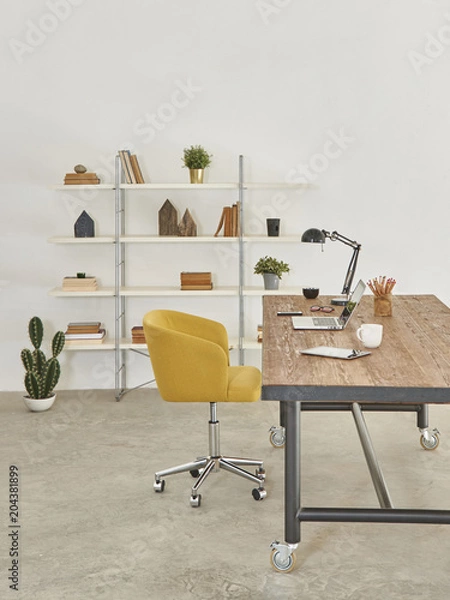 Fototapeta vertical office room style with wood table yellow office chair and devices with bookshelf.