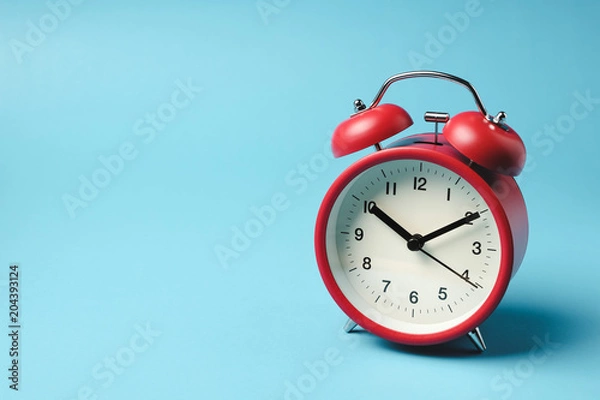 Fototapeta Red vintage alarm clock on light blue color background