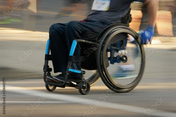 Fototapeta Racing in a Wheelchair. Competitor using a wheelchair in a race. Motion blur.

