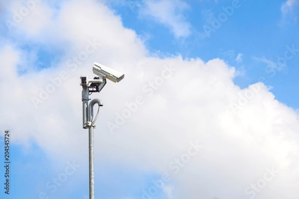 Fototapeta Security camera install corner outside of building with blue sky background.