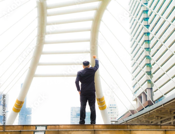 Fototapeta Asian business man is handing up his right handful over his head at central of city for winner concept.
