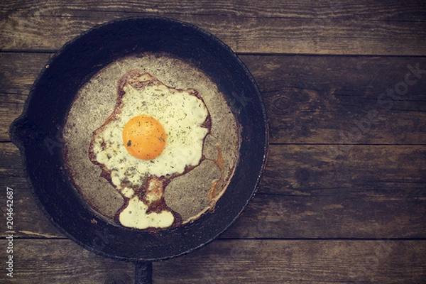 Obraz One fried egg in a frying pan on a wooden background in rustic style close-up and copy space
