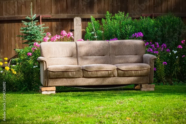 Fototapeta old broken brown sofa set in the garden on the bricks