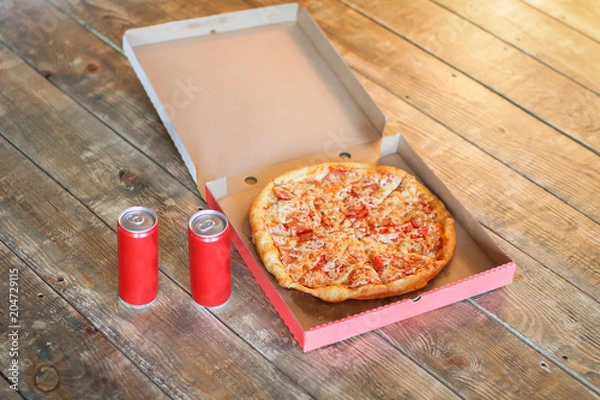 Fototapeta slice pizza in box and can of soda on wood background