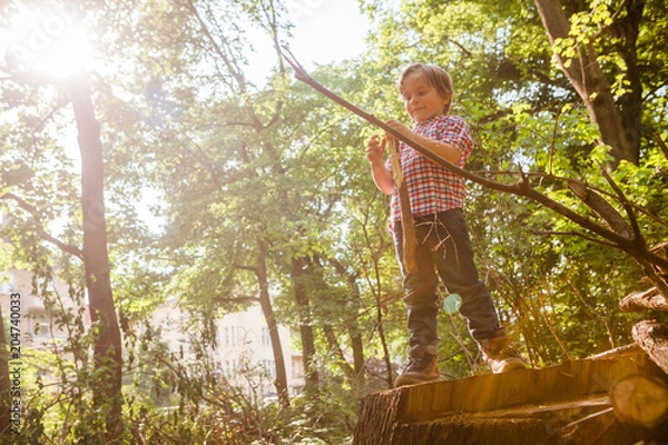 Obraz Little boy playing with some sticks in the forest.