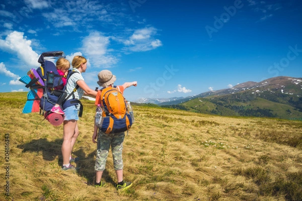 Fototapeta Family of hikers on a trekking day in a mountain valley