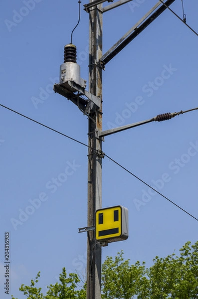 Fototapeta Electrical pole by the railway with train yellow signal.