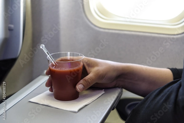 Fototapeta Glas mit Tomatensaft an Bord eines Flugzeugs