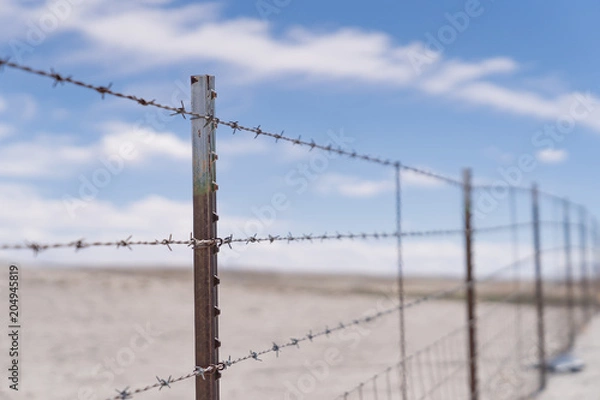 Obraz Barb wire fence in the dry desert country with metal post
