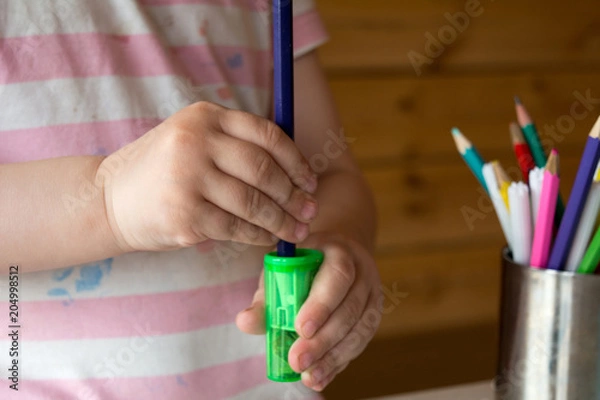 Fototapeta child sharpens colored pencils