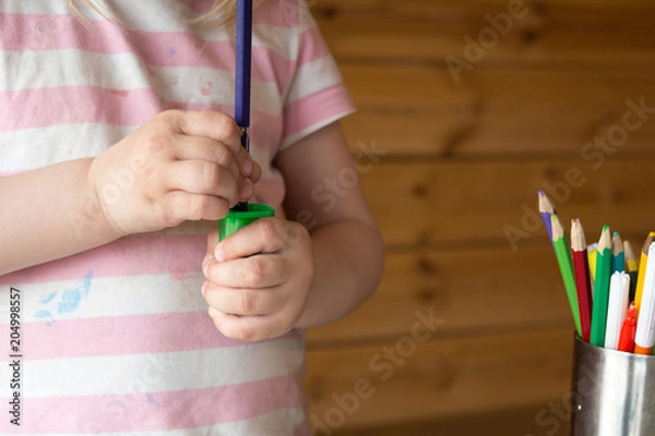 Fototapeta child sharpens colored pencils