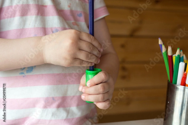 Fototapeta child sharpens colored pencils