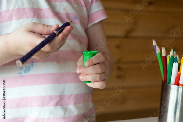 Fototapeta child sharpens colored pencils