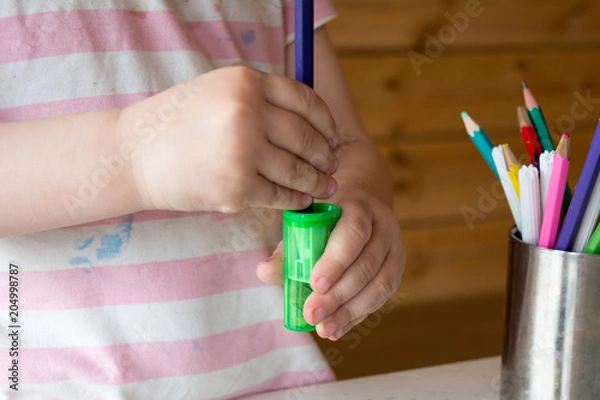 Fototapeta child sharpens colored pencils