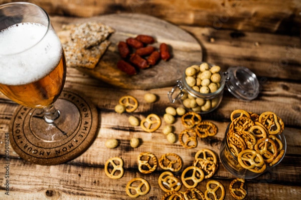Fototapeta Lager beer mug and snacks on wooden table. Nuts, chips. Top view with copyspace