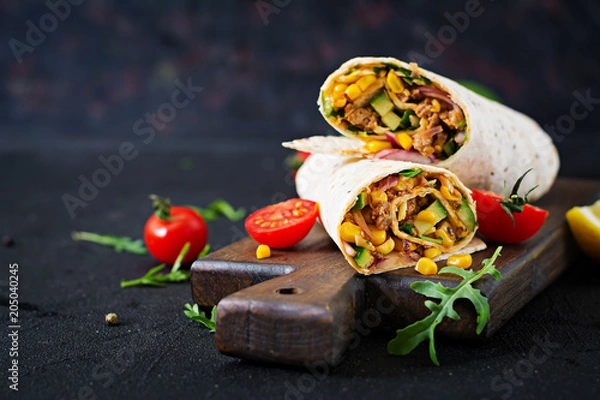 Fototapeta Burrito zawija się z wołowiną i warzywami na czarnym tle. Burrito z wołowiną, meksykańskie jedzenie.