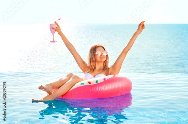 Fototapeta Summer Vacation. Woman in bikini on the inflatable donut mattress in the SPA swimming pool.