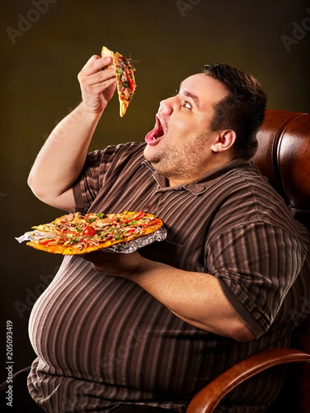 Fototapeta Diet failure of fat man eating fast food slice pizza on plate. Close up of breakfast for hungry overweight person who spoiled healthy food. He can not refuse harmful food.