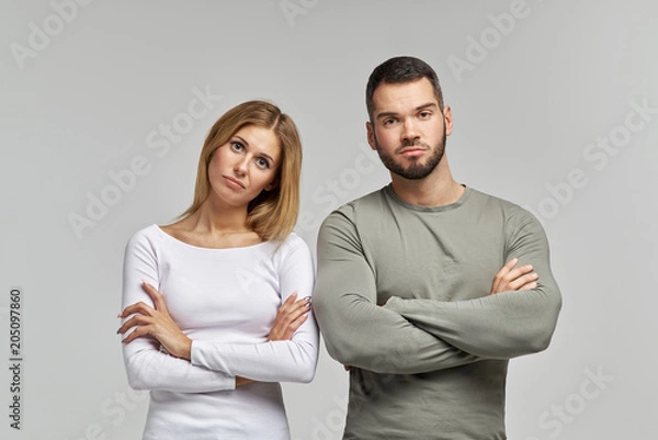 Obraz A young couple of a man and a woman in casual clothes with a upset look and folded their hands on their Breasts