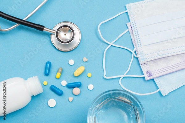 Fototapeta White bottle with different pills, phonendoscope, earloop face masks and glass of water