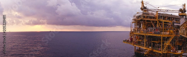 Fototapeta Offshore oil and gas rig platform with beautiful sunset time with storm of clouds in the gulf of Thailand for business industrial concept panorama view