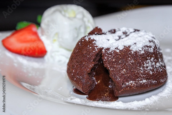 Fototapeta Теплый шоколадный фондант с шариком мороженого и клубникой на белой тарелке.