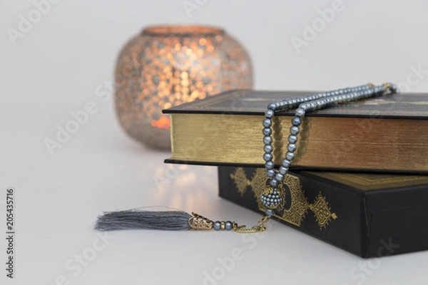 Fototapeta Koran and rosary on the wooden lectern with candle for Islamic concept. Holy book Quran for Muslims for eleven month sultan  Ramadan. 