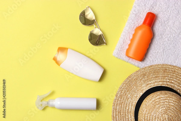 Fototapeta sunscreen, towel, hat, glasses on a colored background. Cosmetics for prevention of sunburn. top view, flatlay 