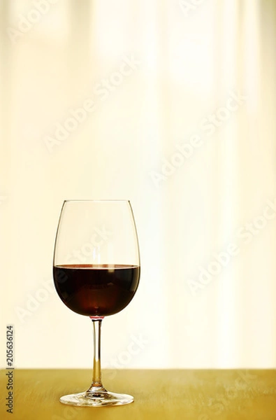 Fototapeta Single Red Wine in Bordeaux-shaped glass on Left Side of Copper Counter Top, with defocused Window and White Curtain, plain background, No decoration, Ambient Warm Day Lighting Studio image 1