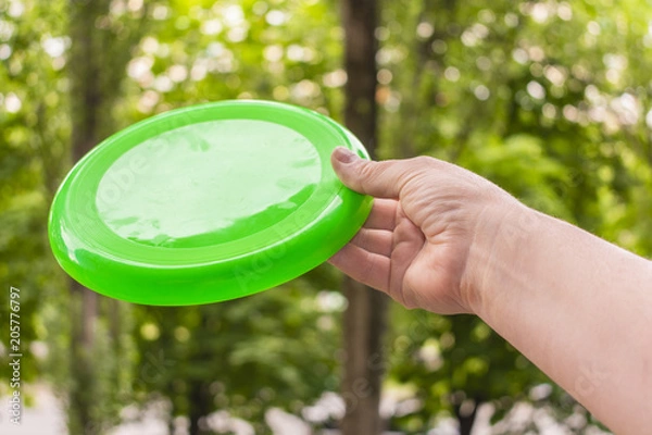 Fototapeta hand throwing a frisbee disc in the park on a summer day