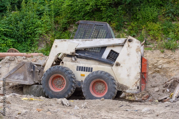 Obraz A close up of a white bobcat s550 or skid loader on construction site.