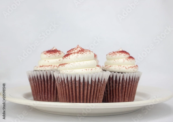 Obraz Yummy red velvet cupcakes with white icing and sprinkles on an isolated white background