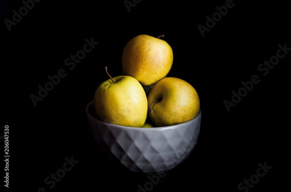 Obraz Bowl of yellow apples. On black background.