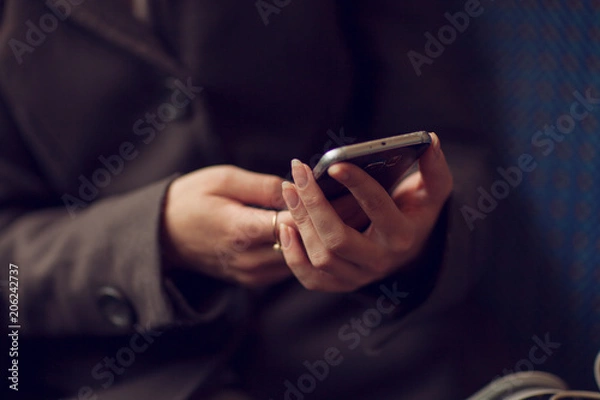 Fototapeta close up woman's hands using a smartphone, dark moody concept, can be used as background